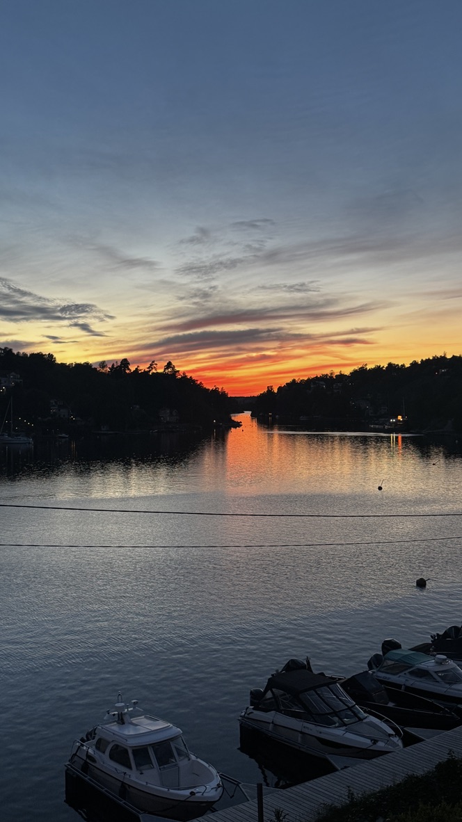 Solnedgång över Skurusundet med båtar vid bryggan